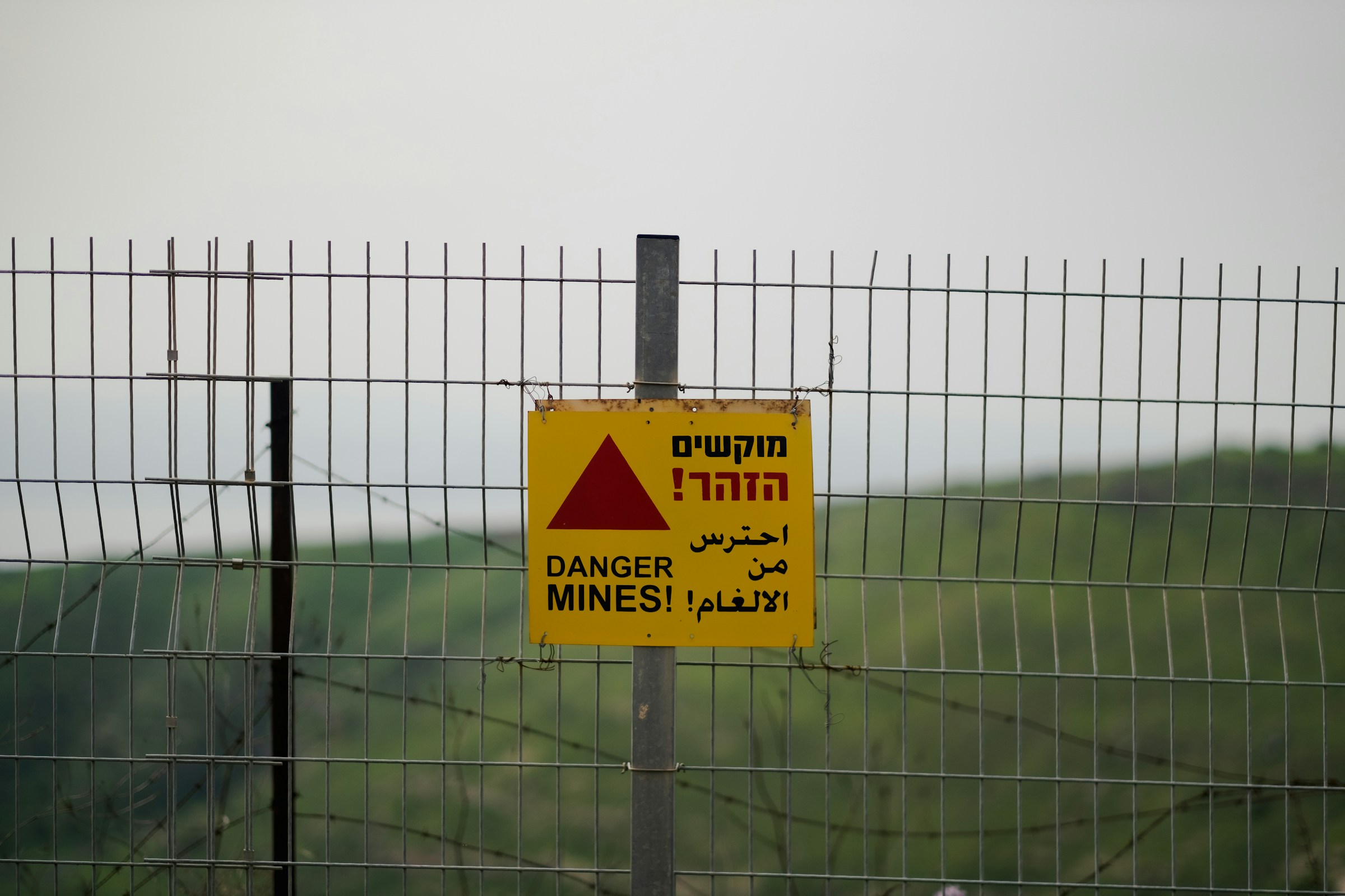 Image of a sign on a fence warning of a minefield - Destination Certification