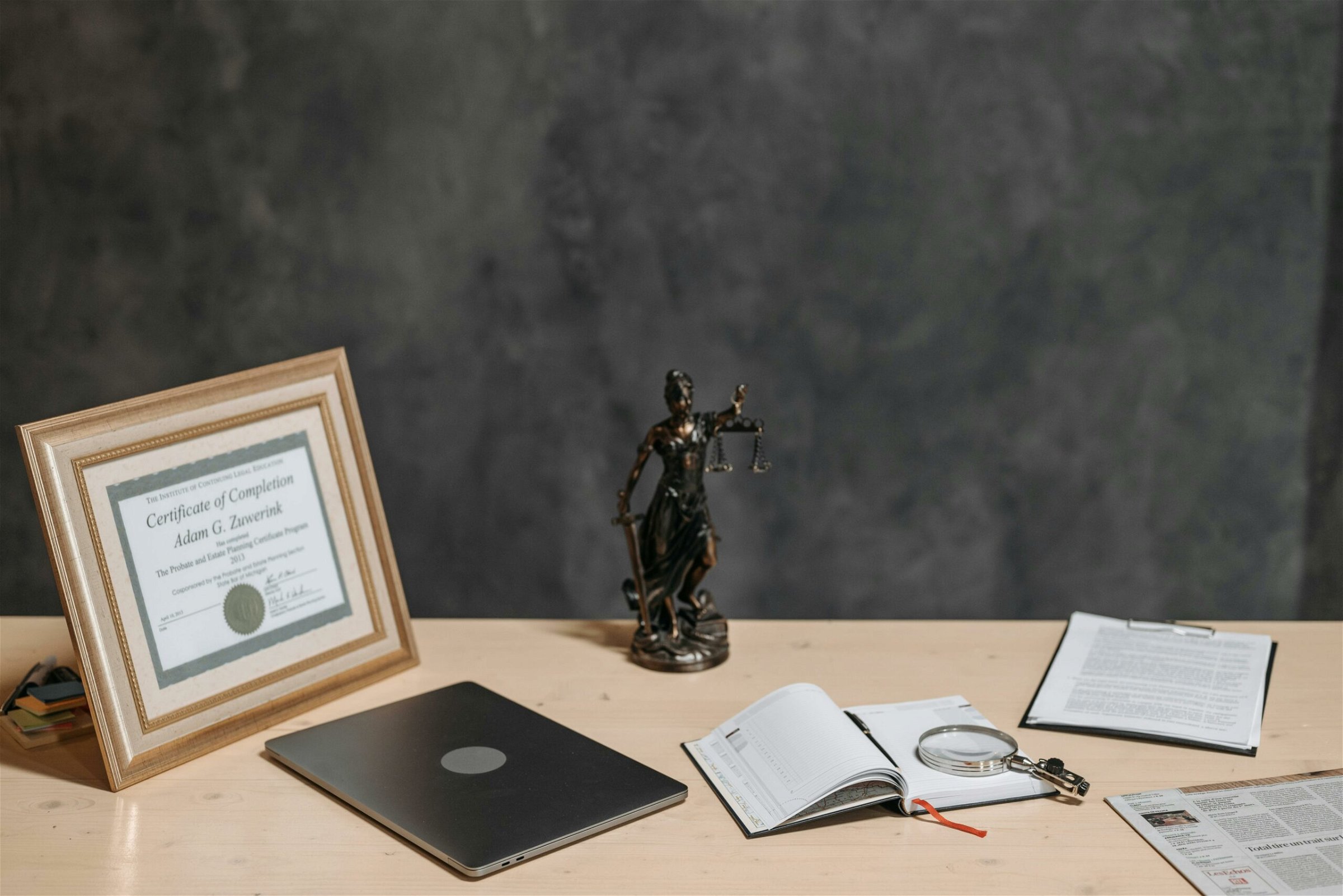 Image of a certification in a picture frame with statue, laptop, book and newspaper on the table - Destination Certification
